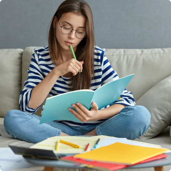 studying-online-concept-serious-young-woman-being-busy-with-remote-freelance-project-sits-comfortable-sofa-writes-notes-holds-textbook-use-laptop-computer-home-with-wireless-internet